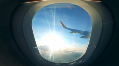 View from an aircraft window with the sun and the plane wing