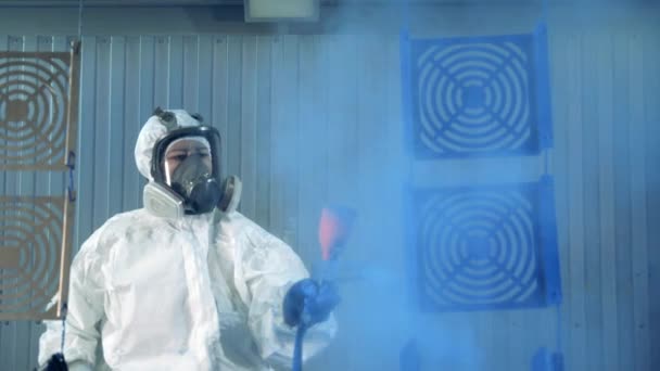 Female worker in safety wear is spraying paint onto metal parts. Industrial painting process at painting factory facility. — ストック動画