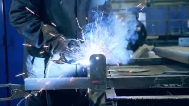 Piece of metal is getting welded by a professional. Professional Welder Working at factory facility.