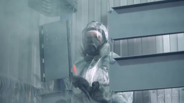 Pieces of metal are being spray-painted by a woman in safety wear. Industrial painting process at painting factory facility. — 비디오