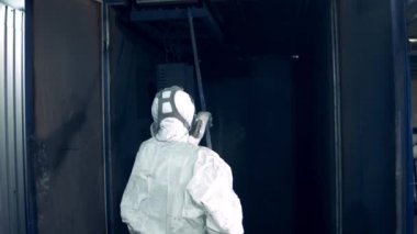 Fabrika boyama tesisinde sanayi boyama işlemi. İşçi metal parçaları endüstriyel fırına koyar.