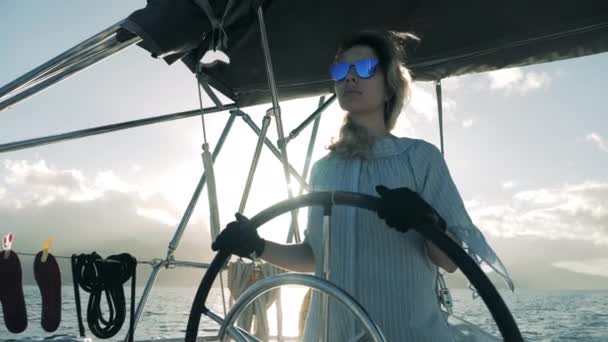 A lady in sunglasses is managing a boat while being at the wheel — 비디오