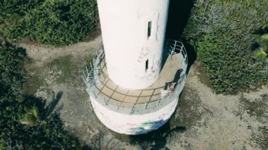 Woman stands on a beacon, looking at sea.