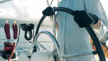 Side view of sailing boats wheel held by a woman