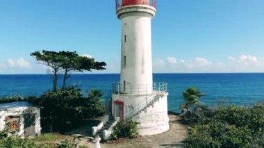 One lighthouse standing on a cliff near blue sea.