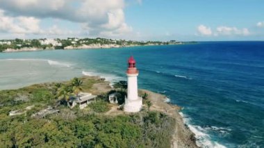 White lighthouse on island near sea.