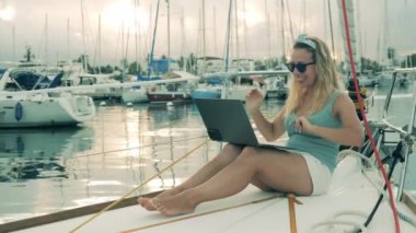 Excited woman is making a videocall onboard of a yacht