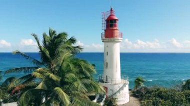 Aerial view on a lighthouse near the Atlantic ocean shore. Big beacon near palm trees on a cliff.