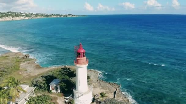 A lighthouse near blue sea on coast. Aerial view on a lighthouse near the Atlantic ocean shore. — Stok video