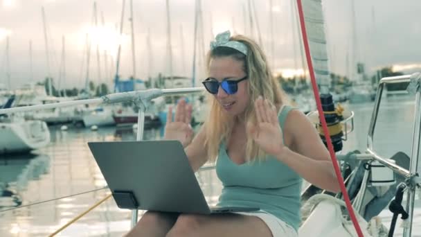 Een vrouw zwaait en lacht terwijl ze filmt vanaf een boot. — Stockvideo