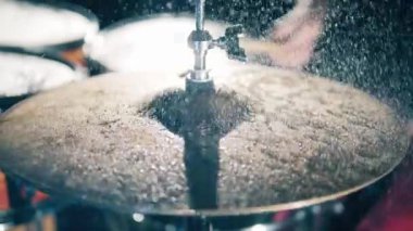 Water splashes on a drum cymbal. Drummer hitting on wet drum cymbal.