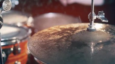 A musician plays drums, hitting cymbal. Drummer hitting on wet drum cymbal.