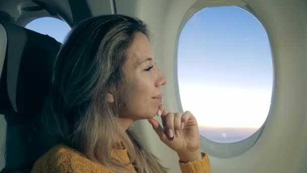 Vista lateral de una señora mirando por la ventana del avión en un primer plano — Vídeos de Stock