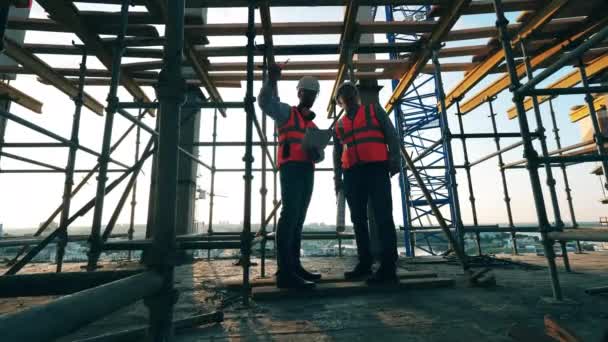 Homens de uniforme discutem a construção em um local . — Vídeo de Stock