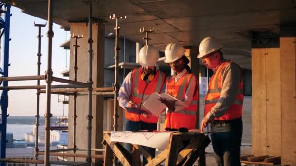 A woman and men work on a construction site, checking blueprint. — 비디오