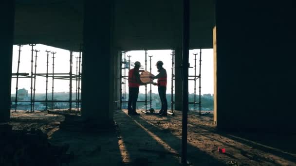 Dva inženýři se podívají na nákres na staveništi. — Stock video