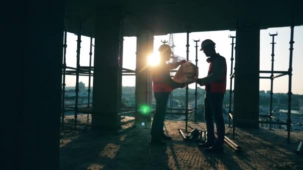 Engenheiros de construção profissionais, arquitetos de construção com um projeto em um canteiro de obras . — Vídeo de Stock