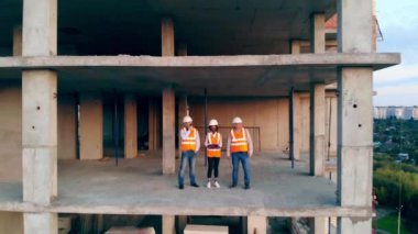 Çok ırklı mühendisler, mimarlar inşaat planını tartışıyor. Çalışan mühendisler bitmemiş bir evde bir şantiyede duruyorlar..