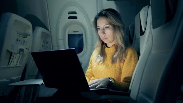 Night flight with a beautiful lady typing on a laptop during it — ストック動画