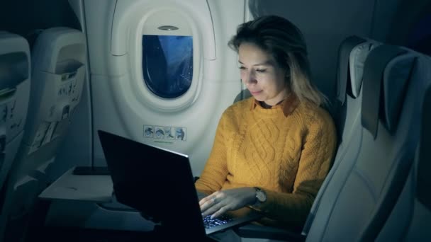 Repülőgép repülés és egy vidám nő gépel egy laptopon a hatósugarában. — Stock videók