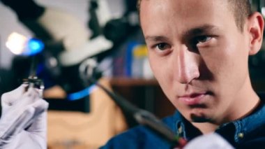 Jeweler uses burner to heat a ring. A goldsmith in jewelry working with ring.