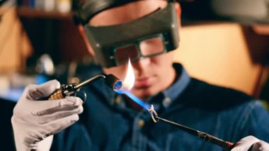 Jeweler welds a ring, using a burner.