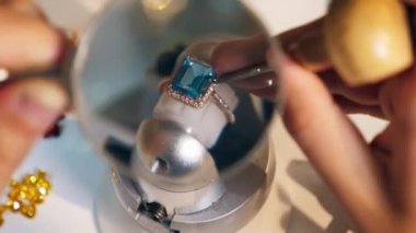 Jeweller, goldsmith uses loupe and tool while working with a ring at a jewellery workshop.