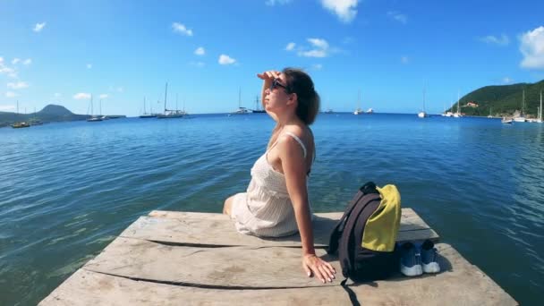 Une femme est assise sur une jetée et regarde le ciel — Video