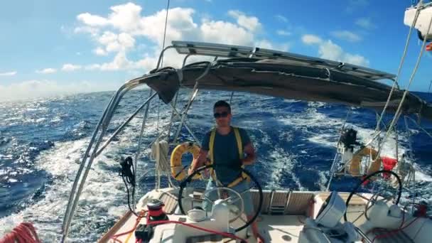 Blue sea with a man navigating a sailboat through it. Ocean, sea sailing boat controlled by a young man. — Stock Video