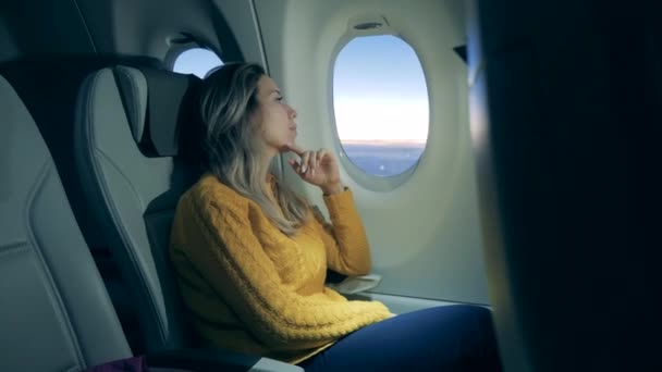 Bir bayan uçak penceresinde güneşin doğuşunu seyrediyor. — Stok video