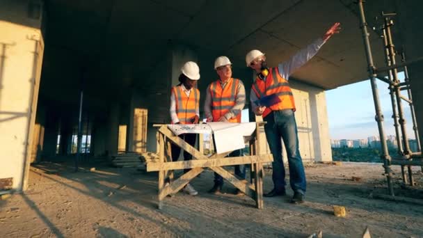 Професійні будівельники обговорюють будівельні роботи на місці . — стокове відео