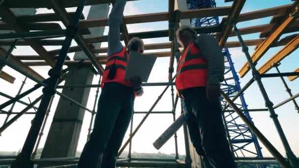 Builders stand in a house, discussing work. — Stock videók