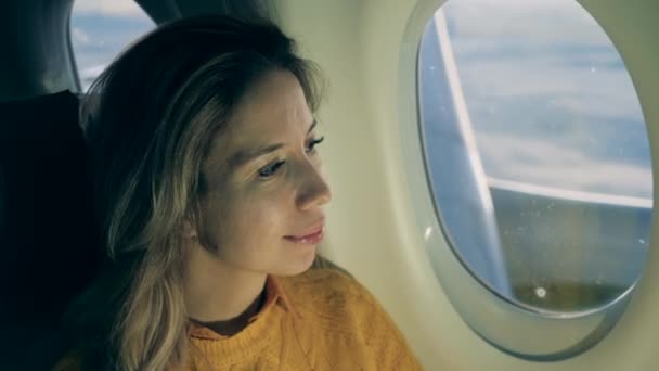 Закрыть лицо женщины, глядя в окно самолета — стоковое видео