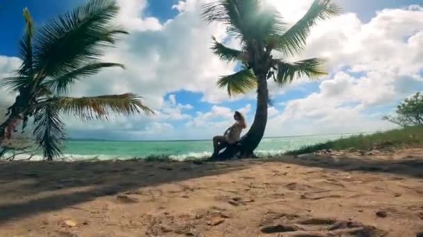 Жінка розслабляється, сидячи на долоні на березі океану — стокове відео