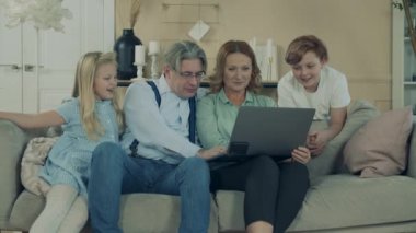 Grandparents are browsing a laptop with their grandchildren