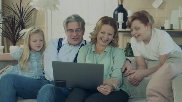 Kids are browsing a laptop with their granny and grandpa — Stockvideo