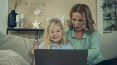 Granny is browsing a laptop with her granddaughter
