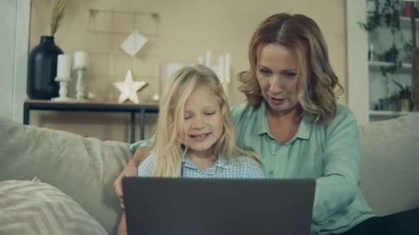 Granny is browsing a laptop with her granddaughter — Stockvideo