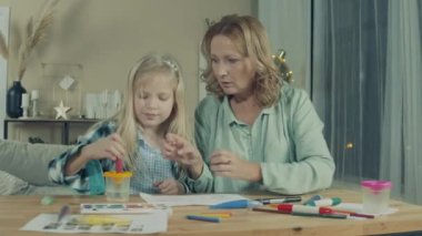 Grandmother is looking at her granddaughter drawing