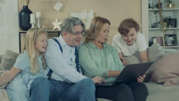 Little kids are having fun with a laptop and their grandparents — Stock video