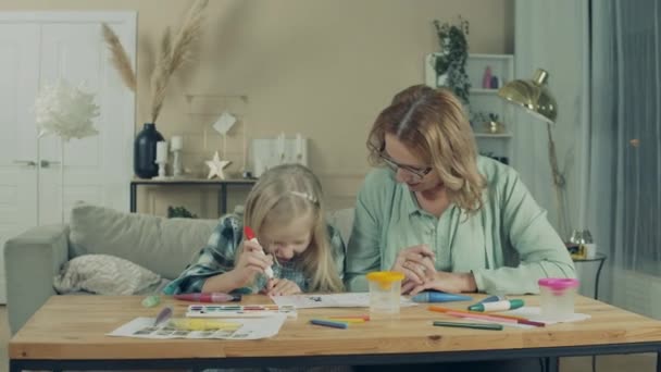 A girl and her granny are drawing at home together — Stok video