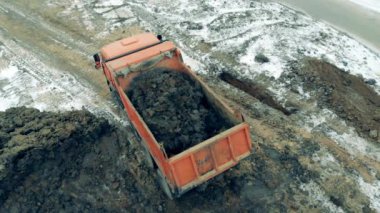 A tractor moves sand into a truck.