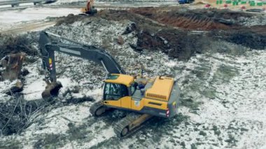Yellow excavator works with stones at a quarry.