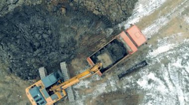 Working excavator loads a truck with stones at a career. Construction excavator work at the industrial quarry.