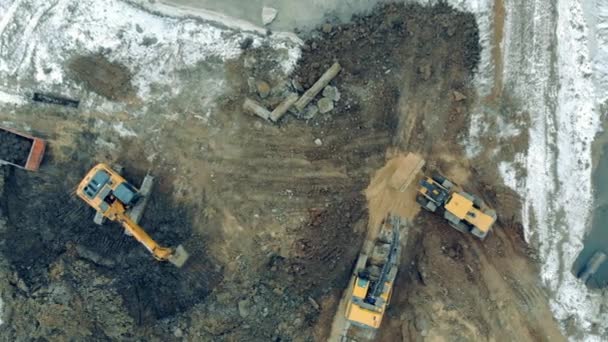 Máquinas industriais que trabalham num estaleiro de construção. Tratores de trabalho escavam a terra em uma carreira . — Vídeo de Stock
