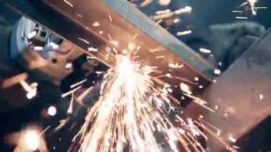 A man cuts metal with a grinding machine.