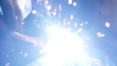 Person works at a factory, using grinder.