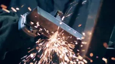 Professional welder cuts metal with angle grinder.