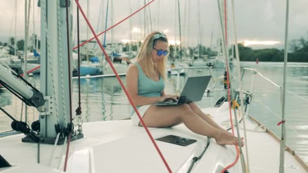 Mujer de trabajo escribe en un ordenador portátil mientras está sentado en un yate . — Vídeos de Stock