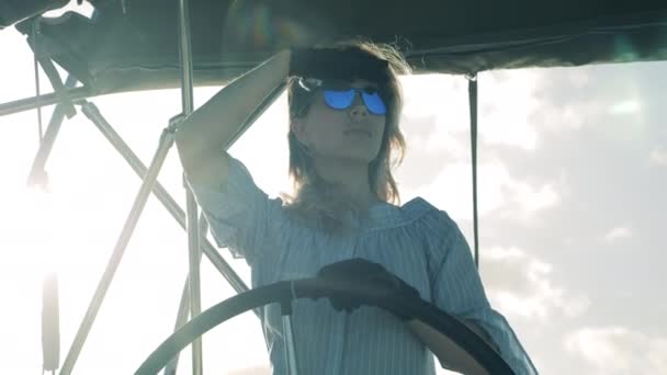 Egy lány vitorlázik egy jachton, és tartja a kormányt. Tengeri utazás, nyári vakáció egy hölgy kapitány. — Stock videók